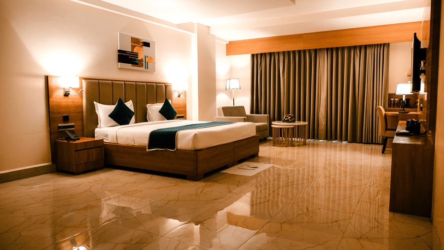 King bed in the Junior Suite with a padded headboard, teal cushions, quilted runner and bedside wall lamps at Ilara Hotels & Spa, Tada.