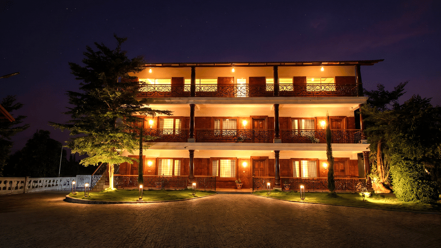 A night view of a brightly illuminated multi-storey resort building with balconies | Vintage Trails By Ilara