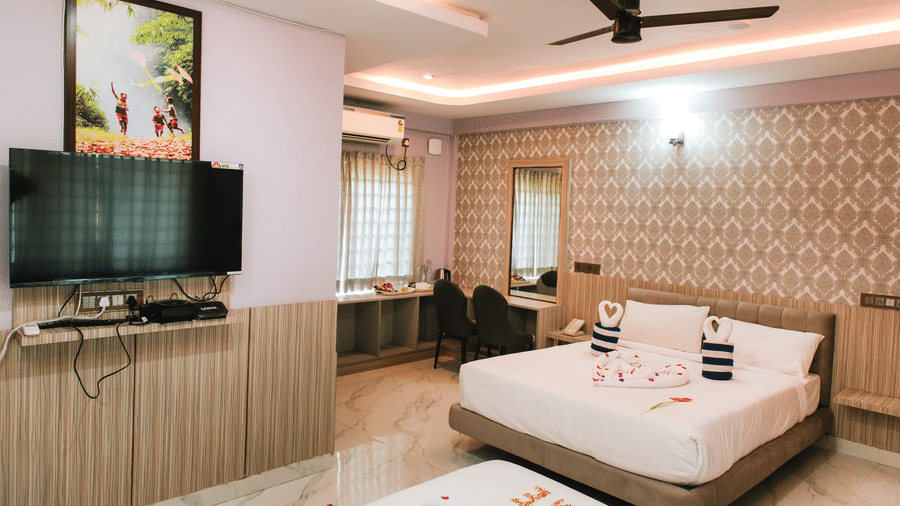 A hotel room featuring a double bed, a wall-mounted television, a ceiling fan, and a patterned accent wall | Vintage Trails By Ilara