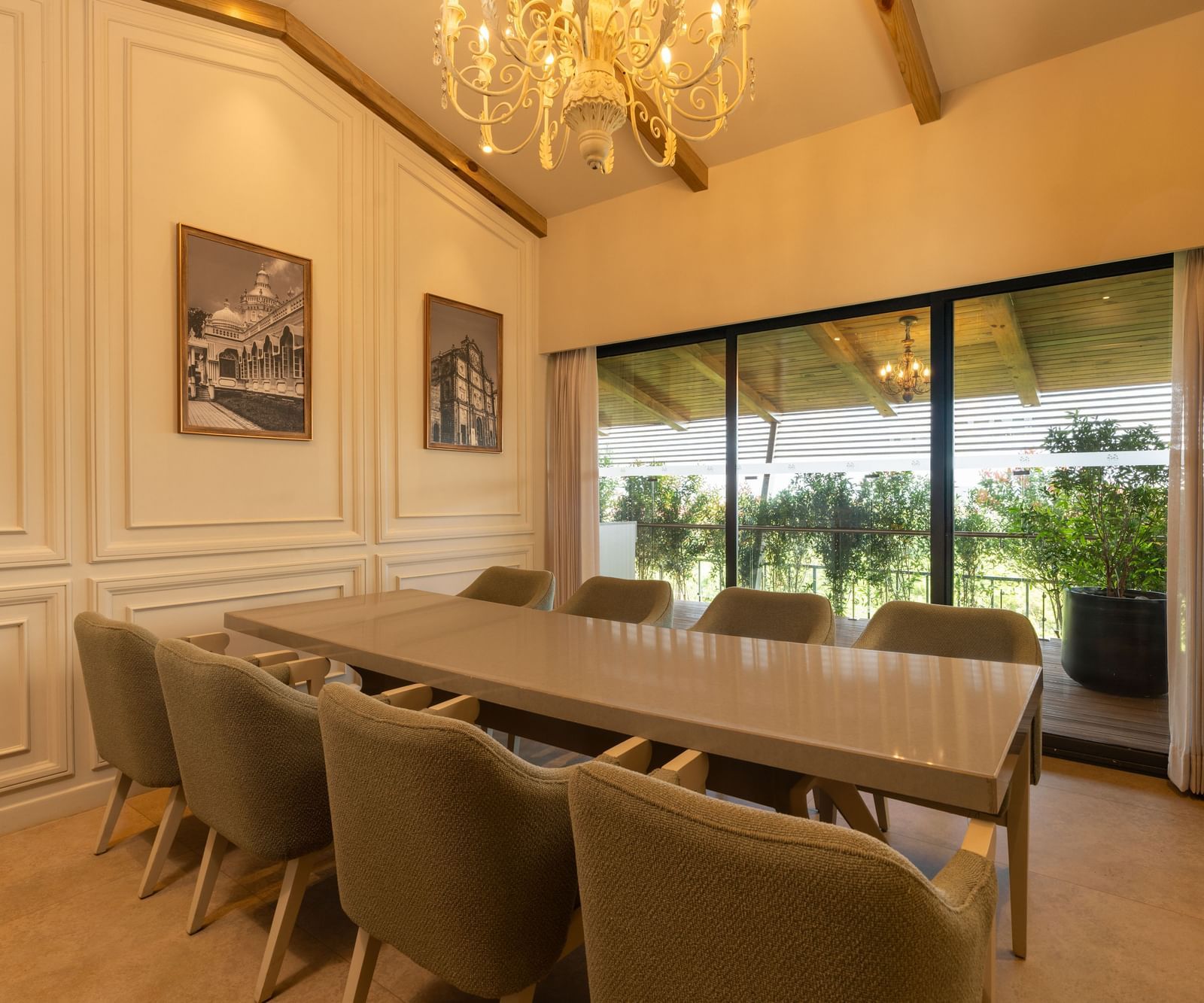 A brightly-lit boardroom at The Evren, Vagator, featuring a long conference table with a window behind it overlooking the lush green lawns.