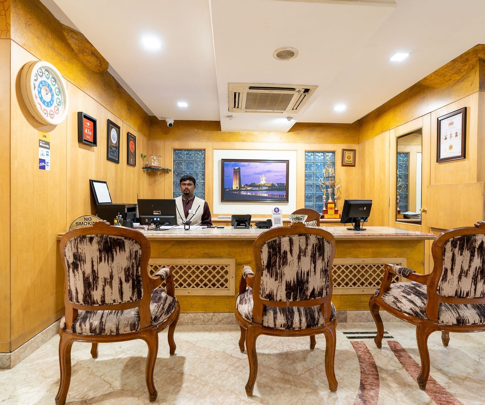 overview of the reception area with a person sitting behind it - Hotel Pai Comforts, JP Nagar