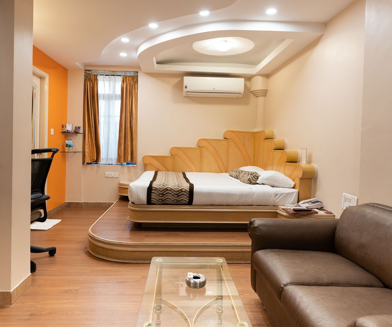 The suite at Hotel Pai Viceroy Jayanagar featuring warm interiors, a queen sized bed and a couch