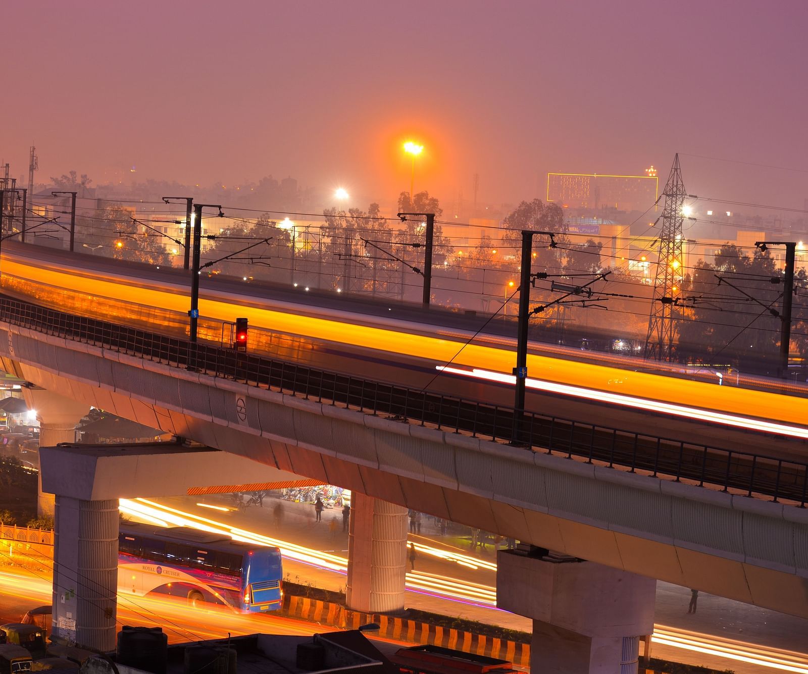 A city metro line at night with traffic visible beneath