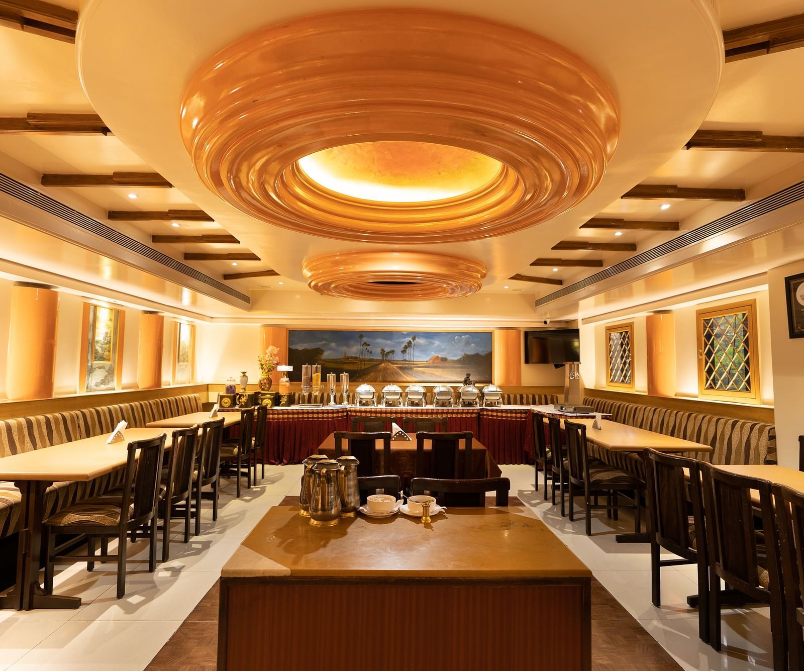 Interiors of the Royal Corner restaurant at Hotel Pai Viceroy Jayanagar featuring a buffet line, dining tables and ambient lighting