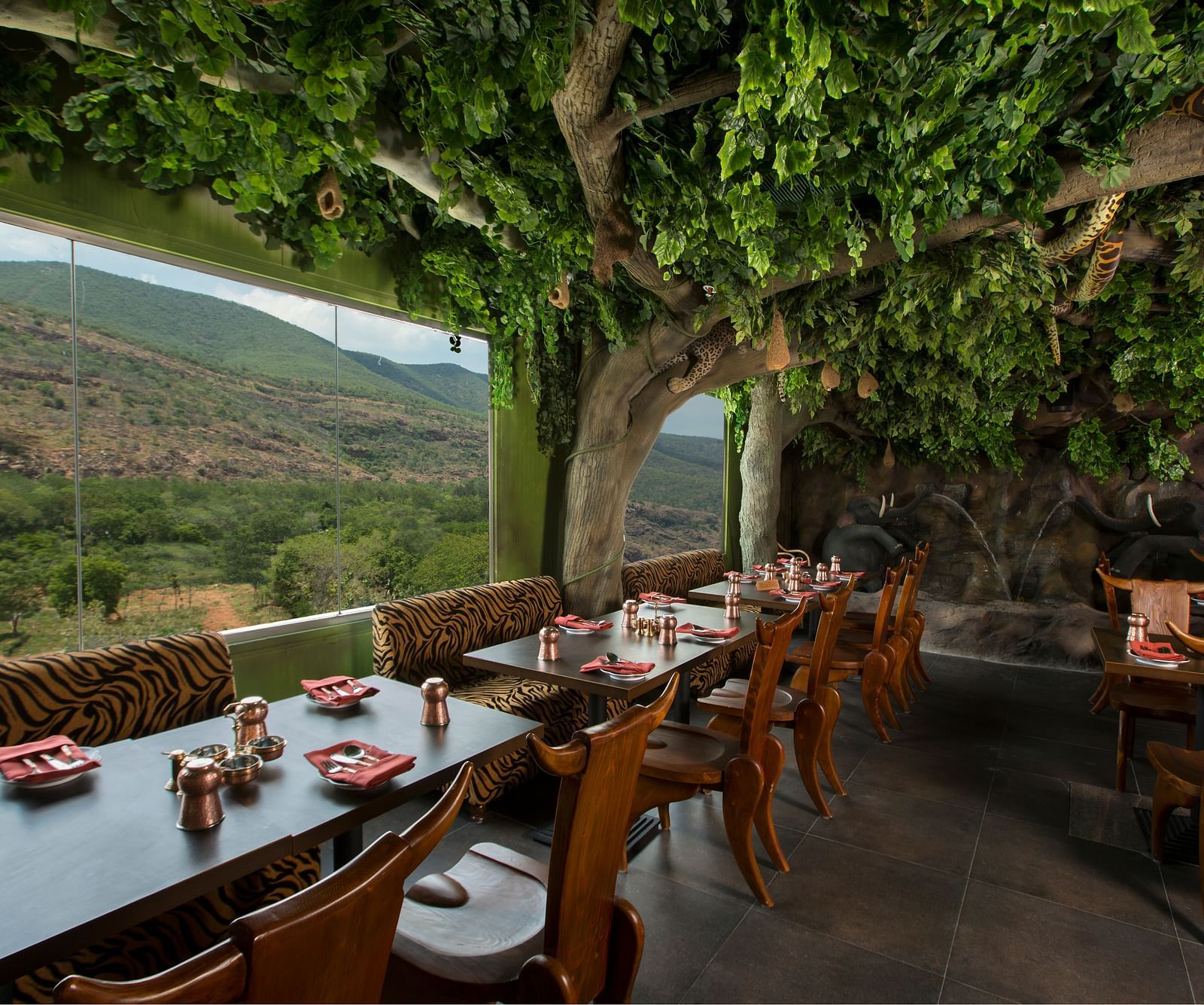 Seating arrangements in front a floor to ceiling glass windows at Gufha Restaurant -Hotel Pai Viceroy Tirupathi