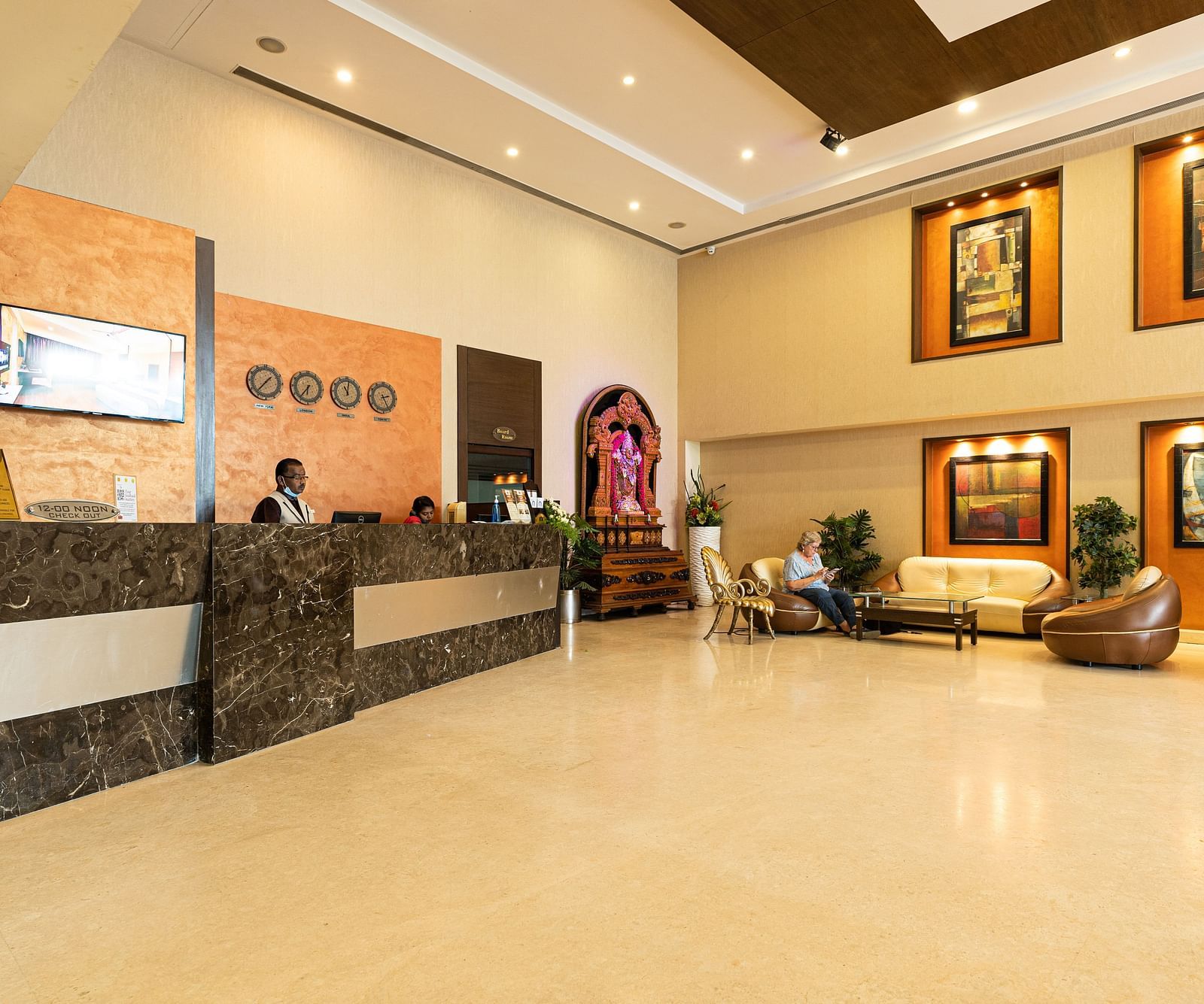 A reception area with people sitting behind the desk - Hotel Pai Vista, Mysore - Mysore Hotel Contact Number