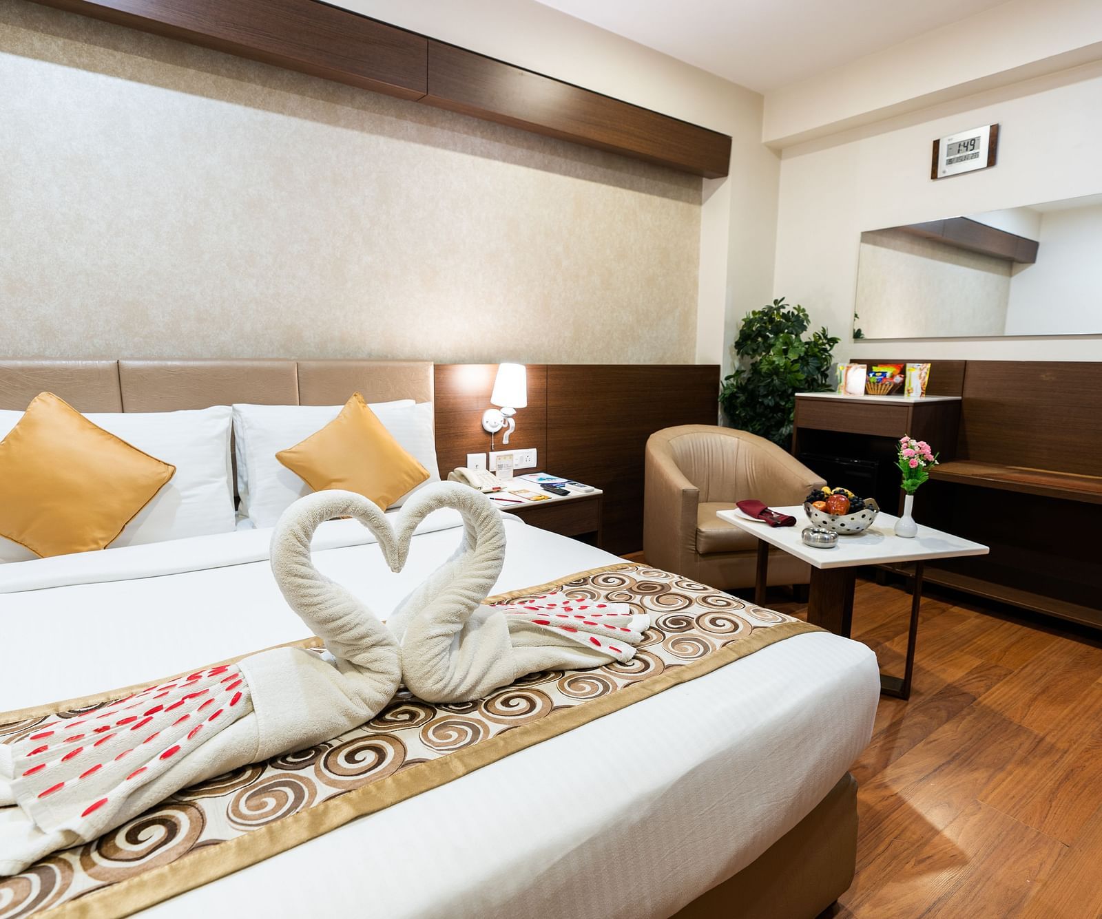 a double bed with dove towels kept on the bed with a sofa next to the bed inside one of the rooms - Hotel Pai Vista, Mysore