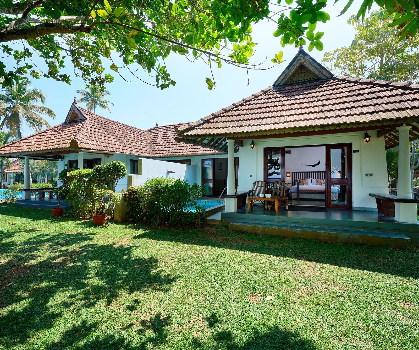 an image of two cottages surrounded by grasslands - Rhythm Kumarakom