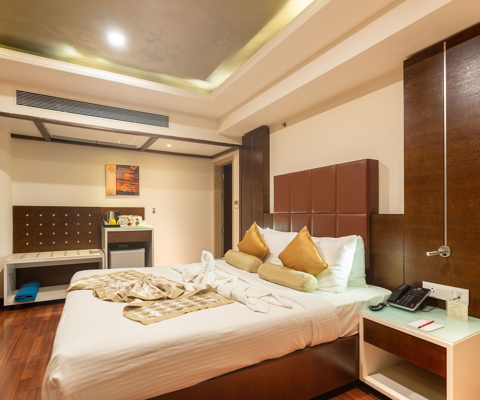 A king size bed with centralised AC and side tables next to the bed inside Club Suite at The President Hotel, Hubli