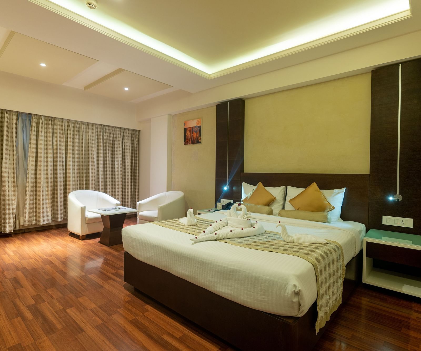 Luxury Room with king size bed, side table, sofa set and table at The President Hotel, Hubli