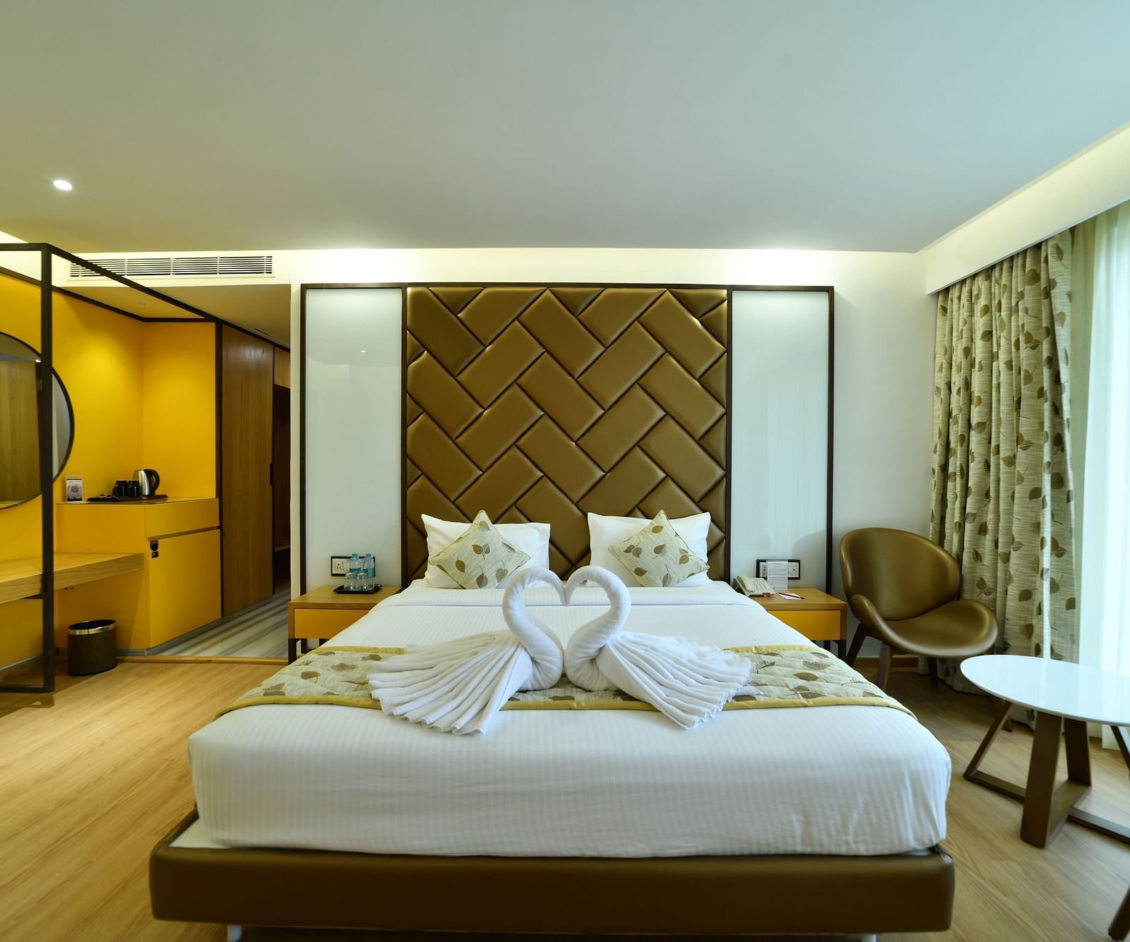 An image of a bedroom with a round mirror and two water bottles placed on the side -The President Hotel, Kumara Park, Bangalore