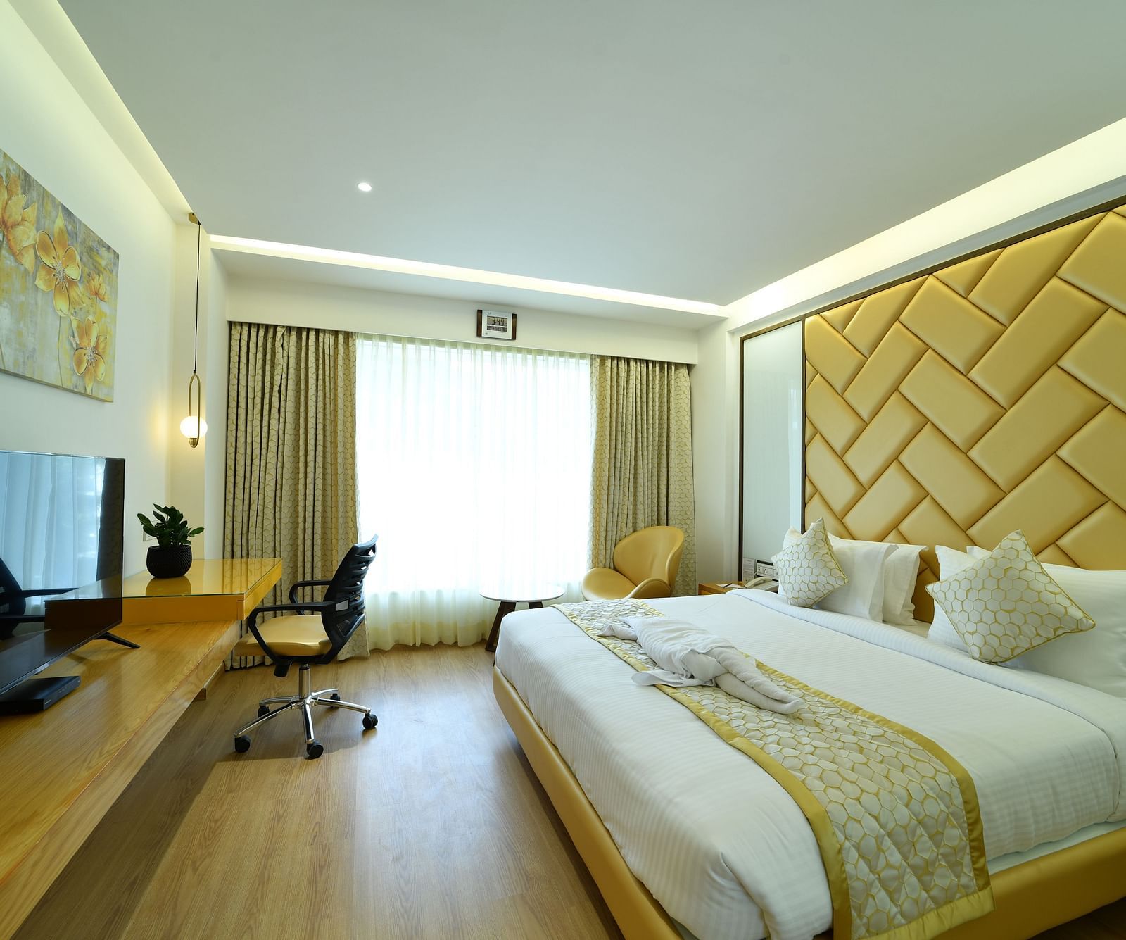 An image of a bedroom with a large bed and a workspace -The President Hotel, Kumara Park, Bangalore