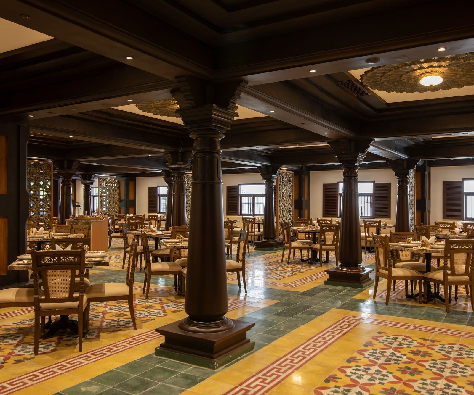 An image of a dining area featuring colourful printed flooring and a flower-inspired ceiling with lights - The President Hotel, Kumara Park, Bangalore