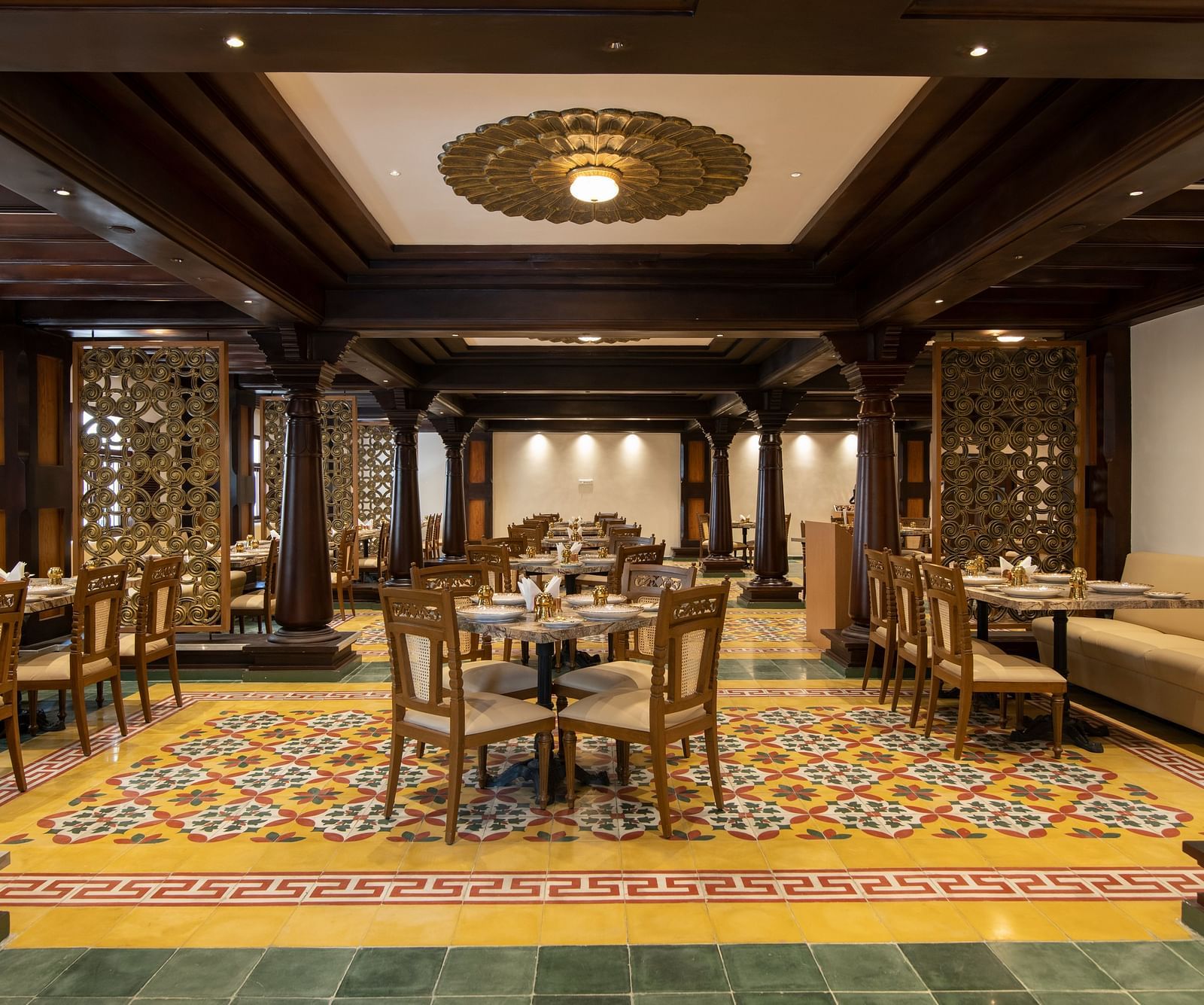 An image of dining room with traditional decor and a colourful patterned floor - The President Hotel, Kumara Park, Bangalore