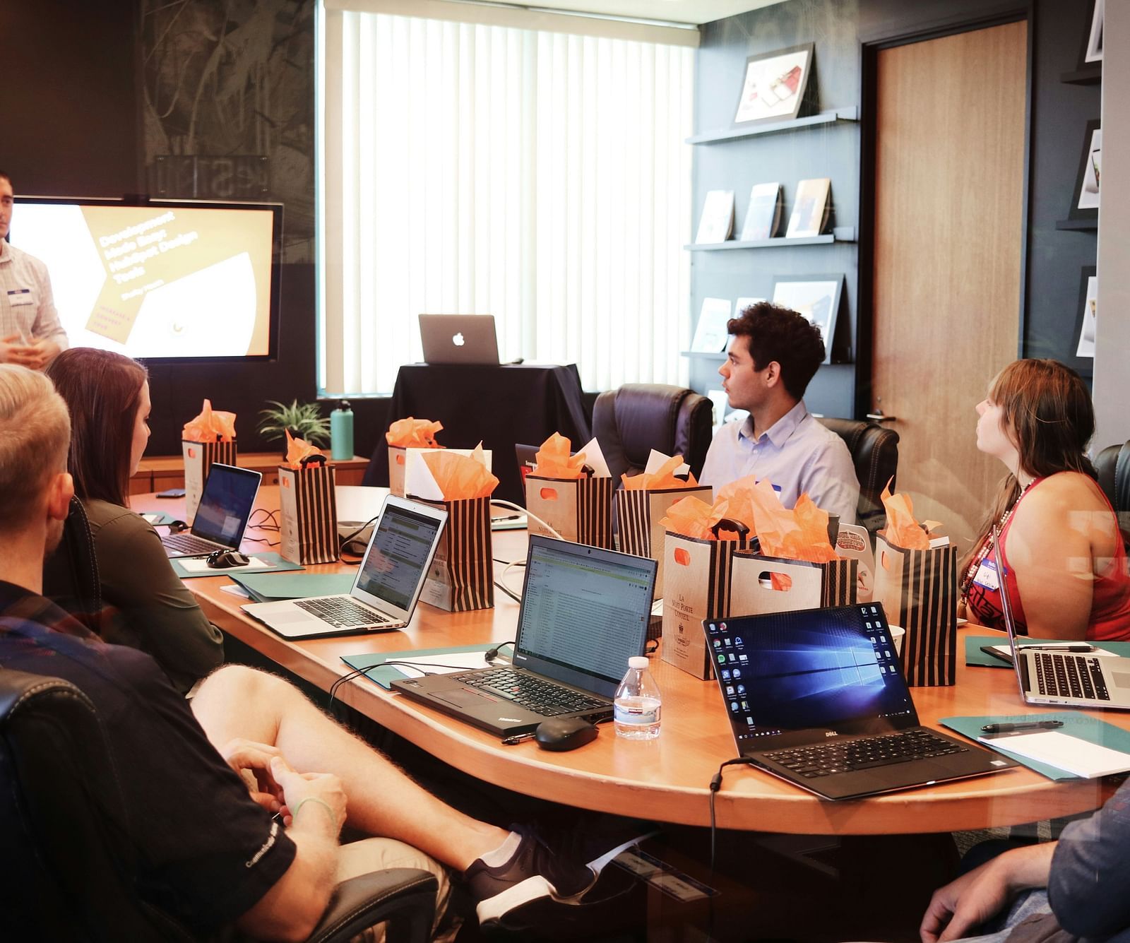 a person conducting a meeting in a boardroom with other people looking on