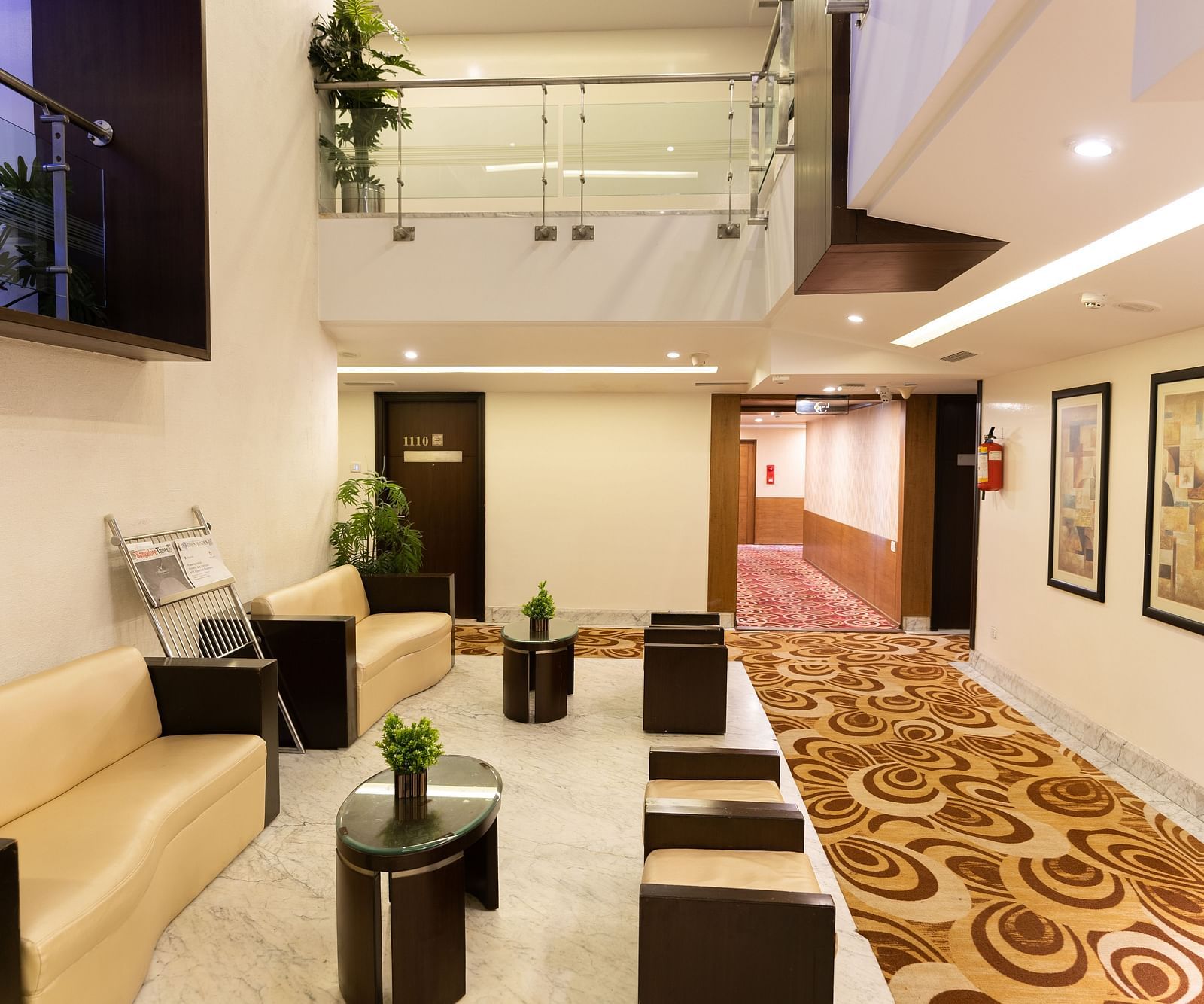 A modern hotel lobby area with comfortable seating, decorative plants, and contemporary art under a bright and welcoming atrium - The President Hotel Jayanagar, Bangalore