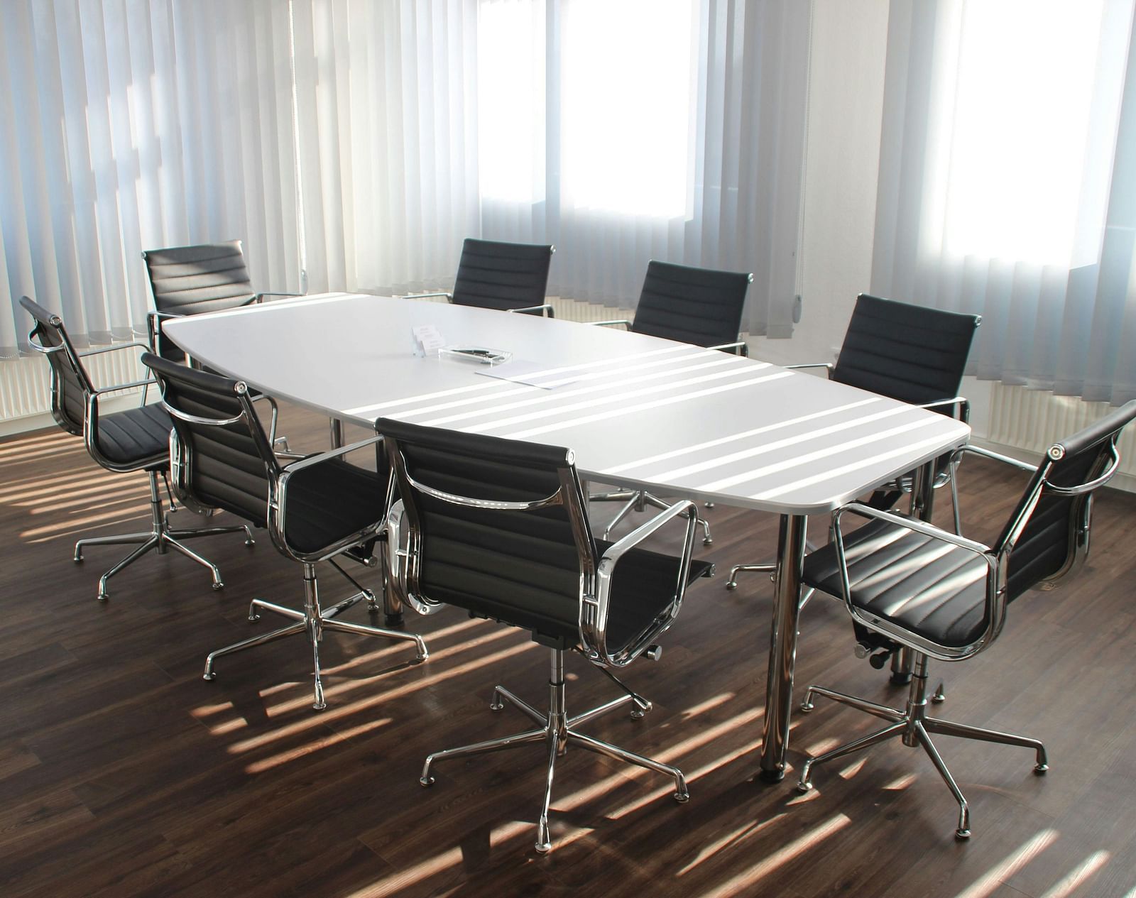 A boardroom with a large table and chairs arranged around it.