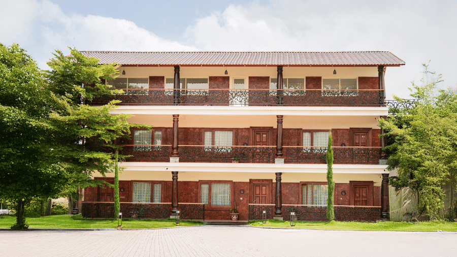 An exterior view of a three-storey wooden resort building featuring multiple balconies and windows | Vintage Trails By Ilara