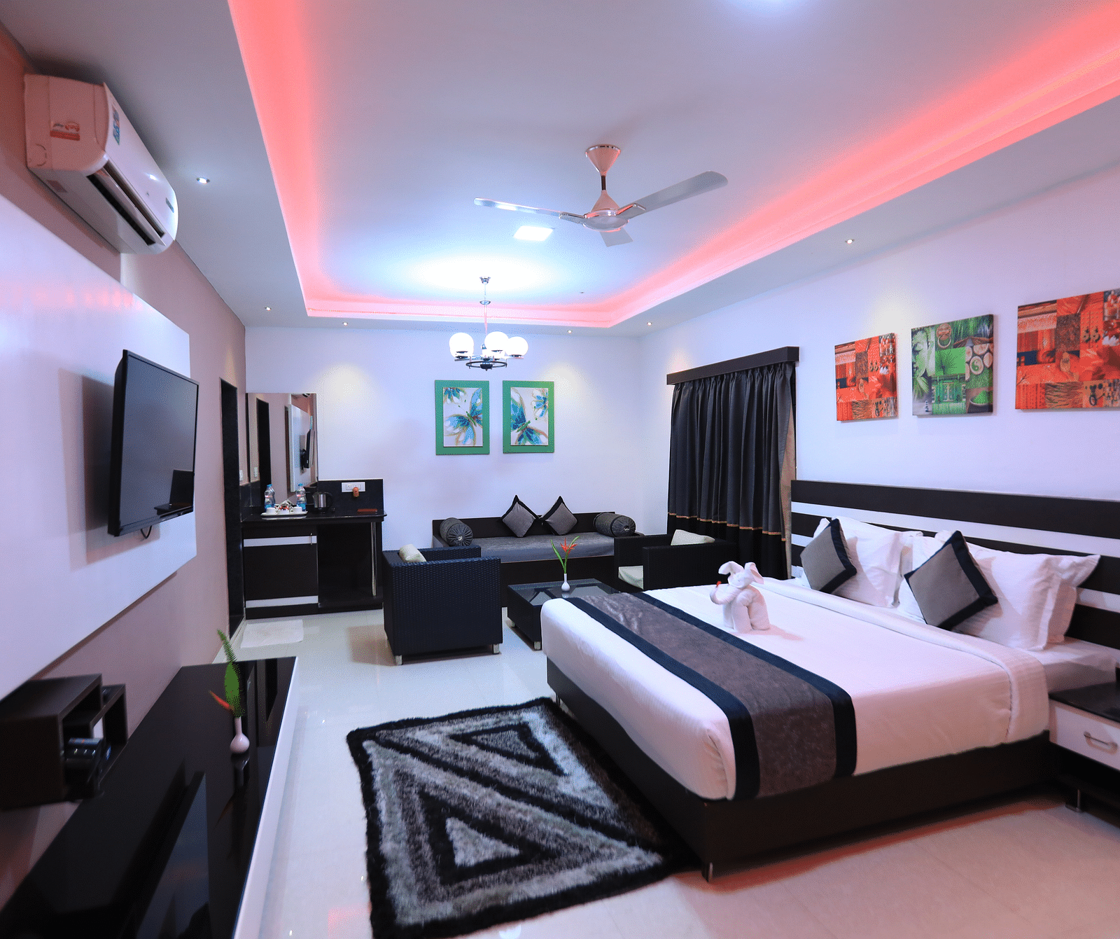 Image of a room with a bed with photo frames above it and a television in front.