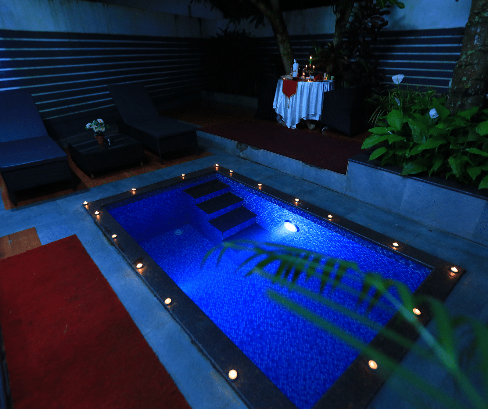 Image of a swimming pool at night with lights on the sides of the pool at Parampara Resort & Spa, Kudige, Coorg.