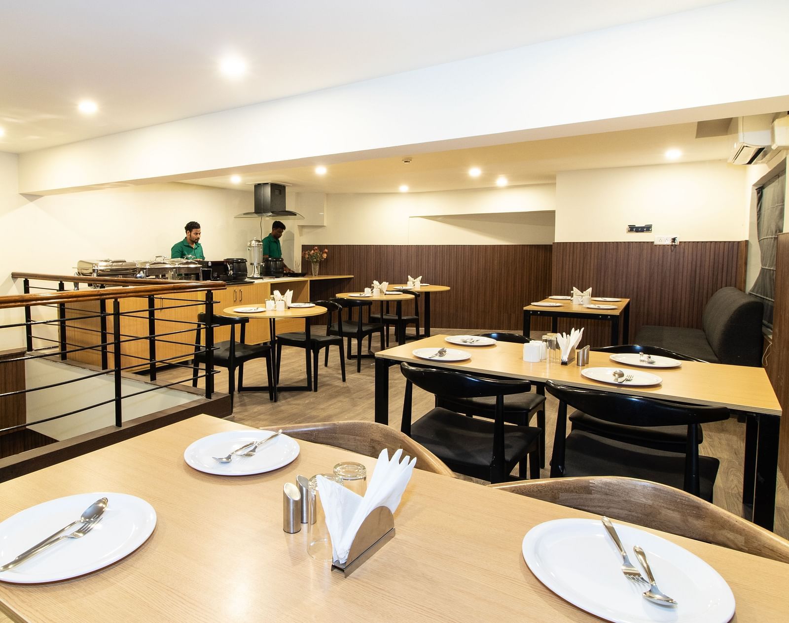 A dining area with wooden tables and chairs in a warm inviting setting - Sanctum Suites Richmond Road, Bangalore