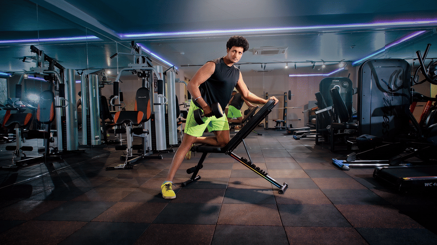 Guest performing a dumbbell exercise at an adjustable bench in the fitness centre, with strength machines and mirrors at Ilara Hotels & Spa, Tada.