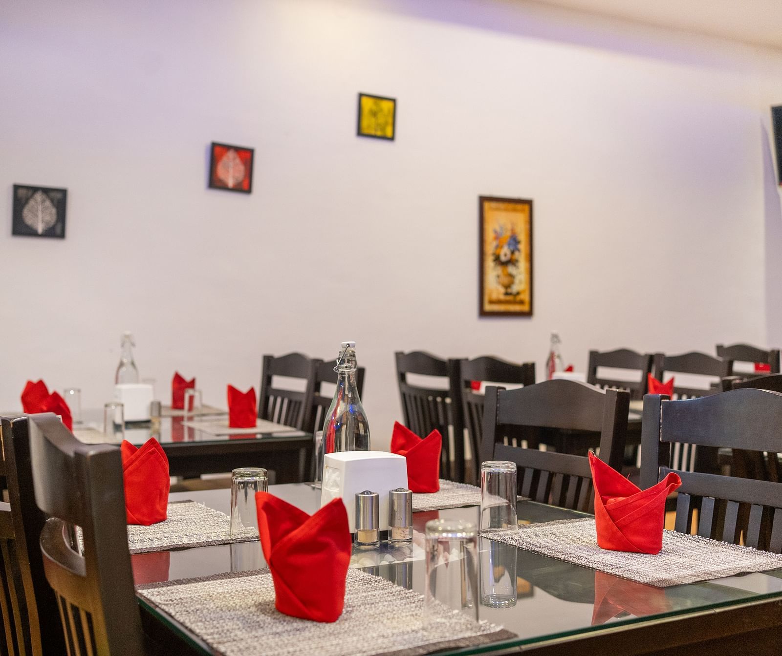 Image of a dining space with tables and chairs and frames on the wall at Coorg Jungle Camp Backwater Resort, Kushalnagar.