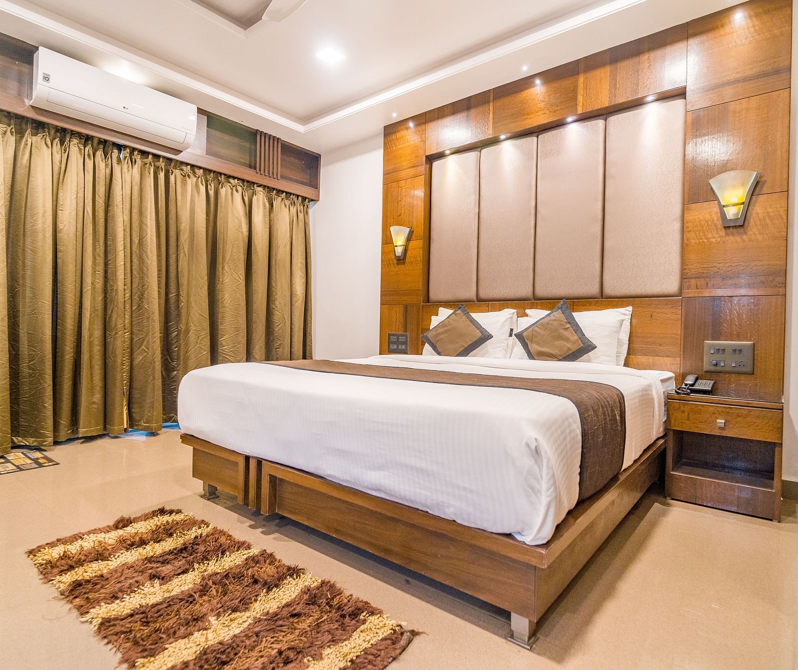 Image of a room with a bed with a rug in front of it and a window on the side at Hotel Altitude, Madikeri.