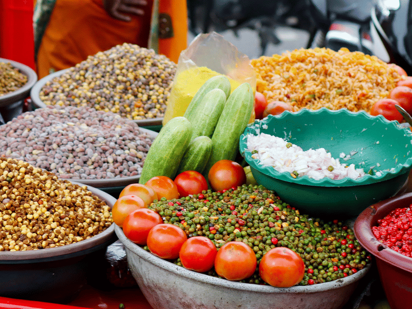Street food vendor’s stall showcasing various metallic trays filled with savoury snacks, fillings and garnishes.