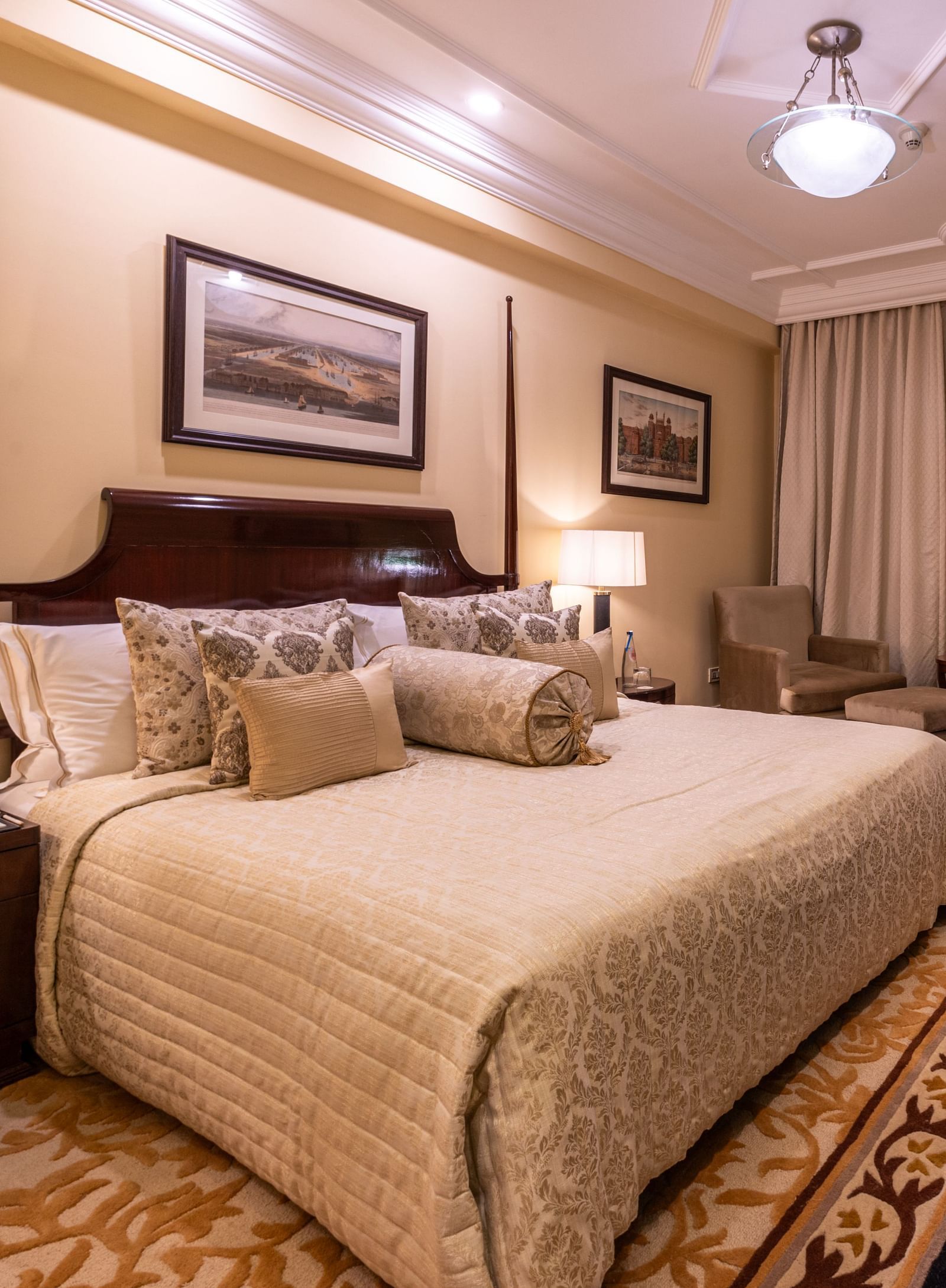 image of the bedroom of the heritage parlour room with a king size bed and beautiful photoframes hung on the wall - The Claridges New Delhi