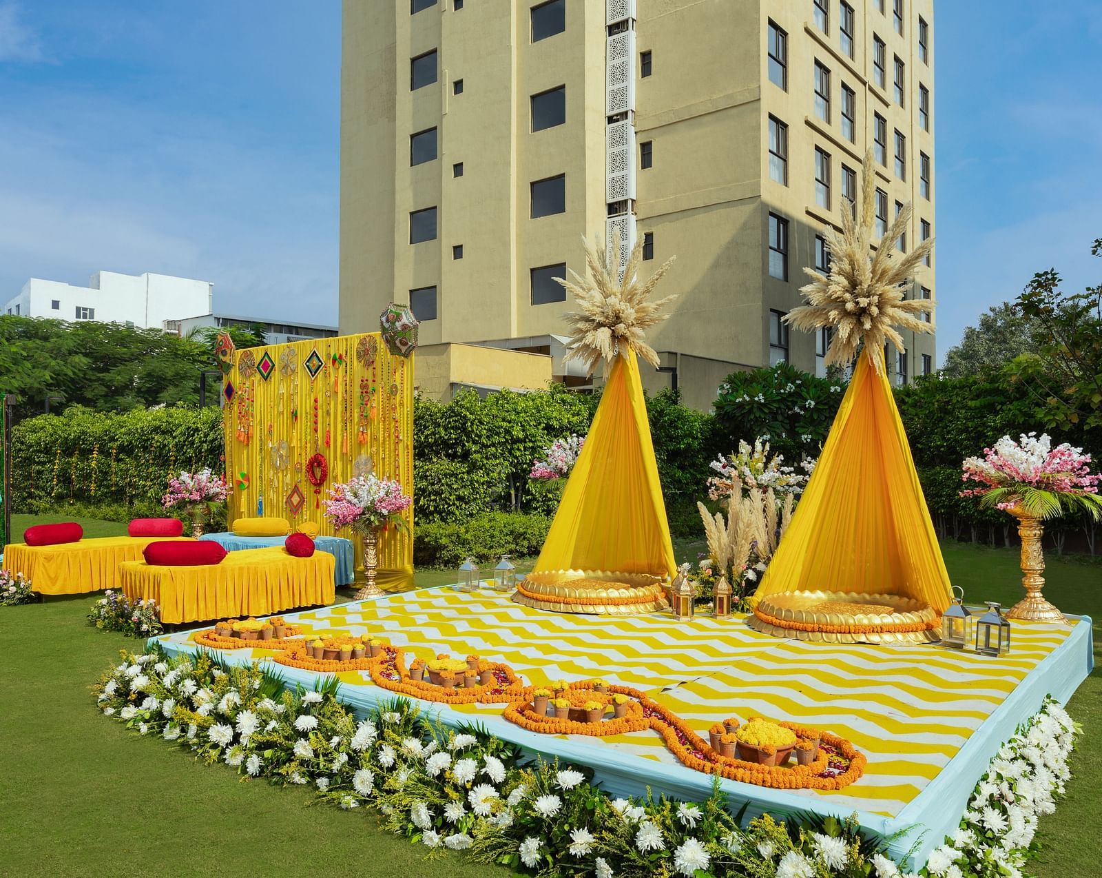 a stage set with two specially decorated seats and more seating arrangements beside the stage - The Hideaway Banquets & Lawns, Greater Noida