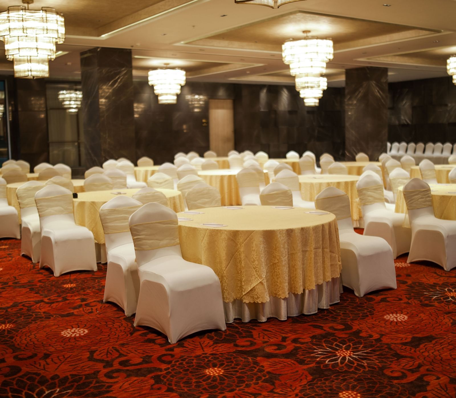 Banquet setup with round tables and white chair covers on a vibrant red carpet at Ramada by Wyndham Sonipat Murthal