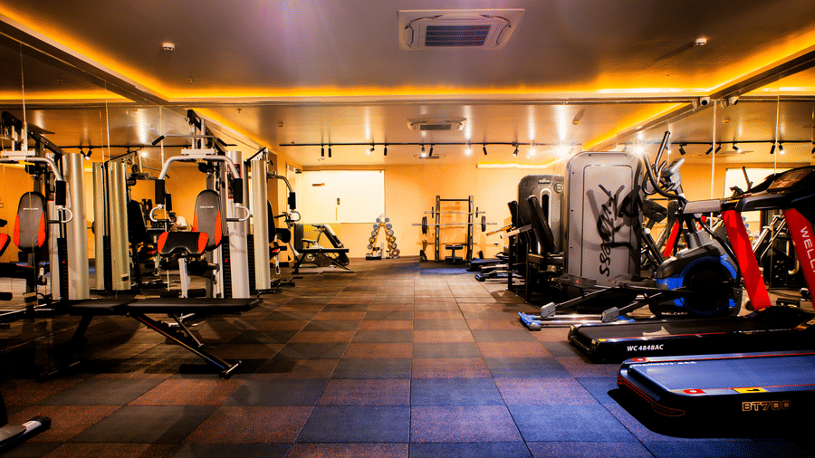 Fitness centre with multi-station gym equipment, treadmills, cross trainers and racked weights on rubber flooring at Ilara Hotels & Spa, Tada.