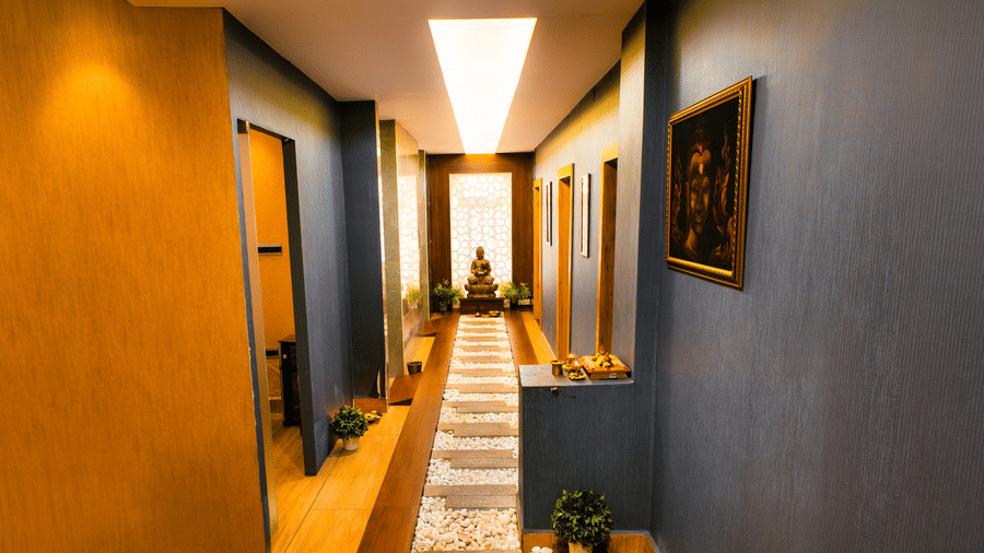 Spa corridor with a pebbled walkway, stepping stones, a Buddha statue before a lattice screen and a Buddha painting at Hasta Spa, Ilara Hotels & Spa, Tada.