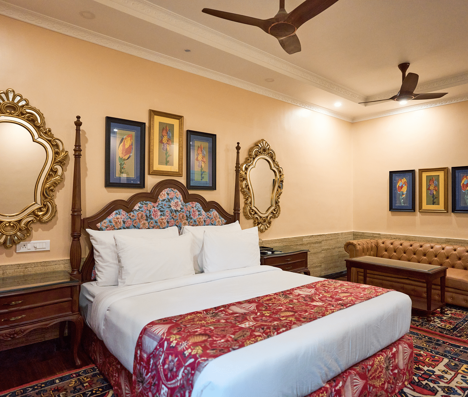 A spacious room with a large bed on one side and cushioned seating furniture on the other, adorned with wall-mounted frames for decoration at Mayfair Manor, Alibag