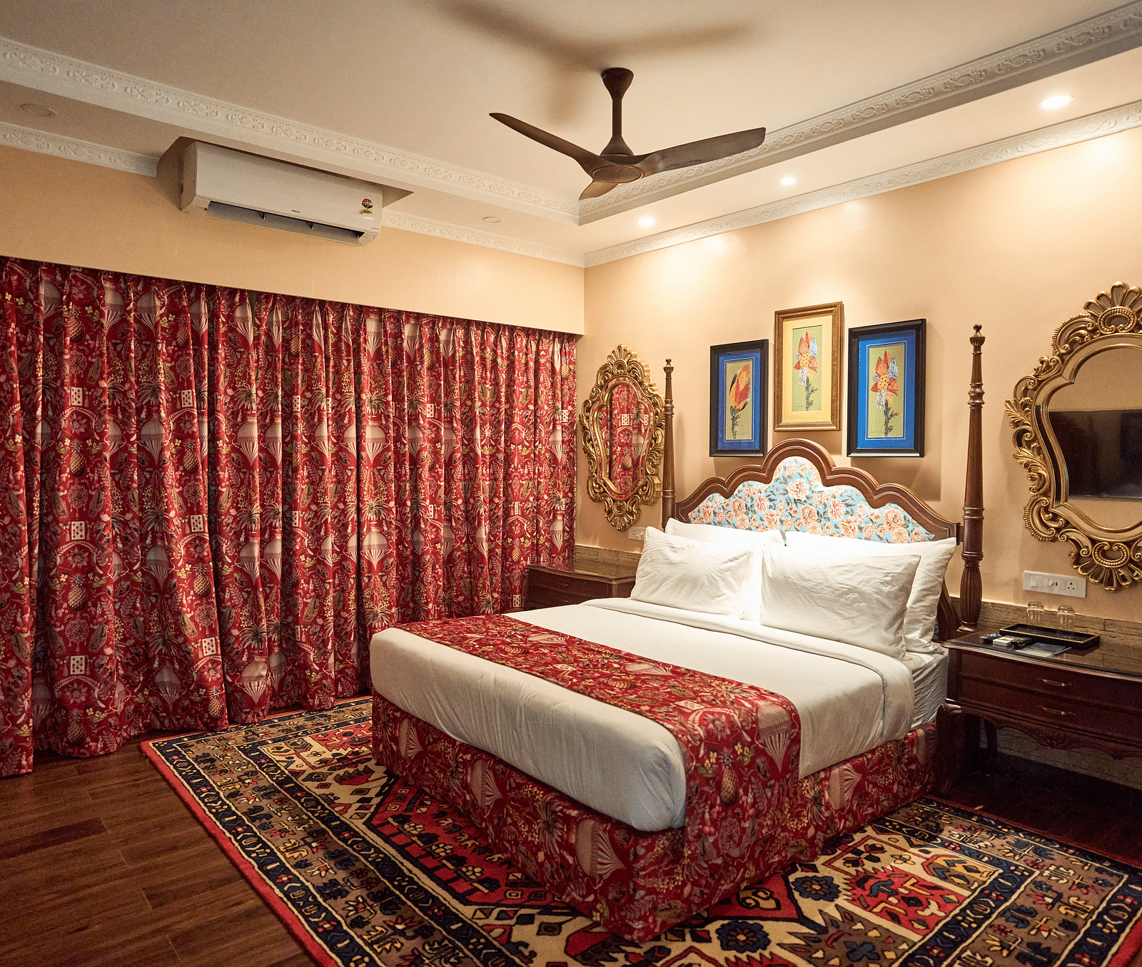 A spacious room featuring a large bed, wooden bedside tables, and windows draped with curtains at Mayfair Manor, Alibag