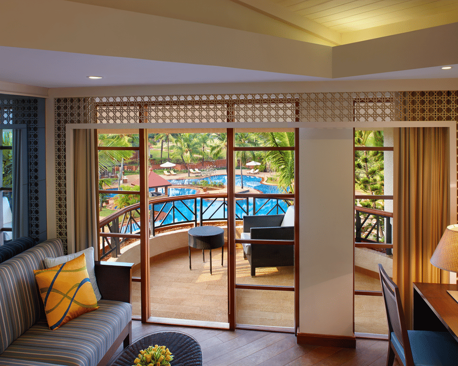 a living Room with sofas, table and access to the balcony - Caravela Beach Resort Goa