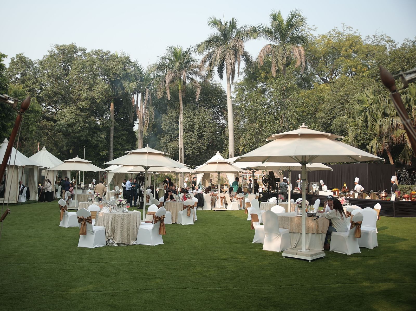 Image of the spacious garden at The Claridges New Delhi, featuring an open area with a clear sky, surrounded by large trees