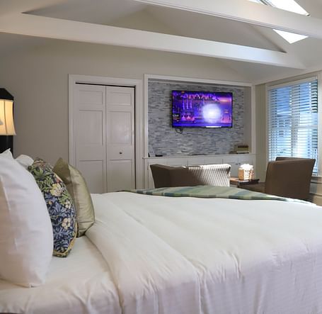 Hotel room with white bed, TV, and large windows at Hartstone Inn