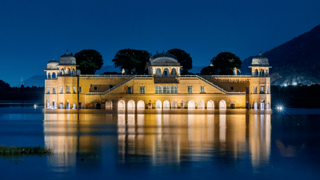 Illuminated Jal Mahal glows against the night sky, reflecting softly across the still waters of Man Sagar Lake in Jaipur