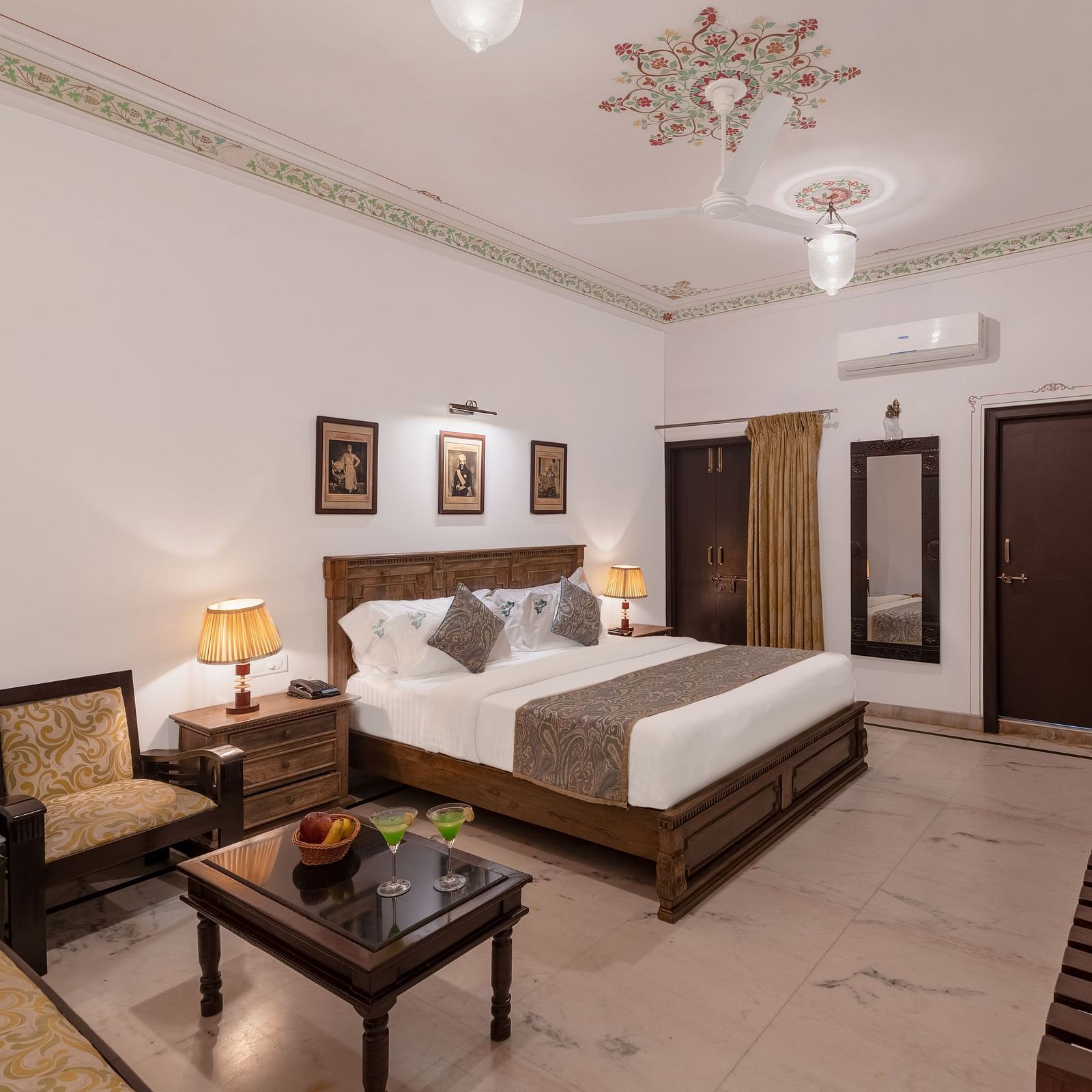 A spacious bedroom at Panna Vilas Palace, featuring a wooden table, cushioned furniture, and warm lighting | Panna Vilas Udaipur