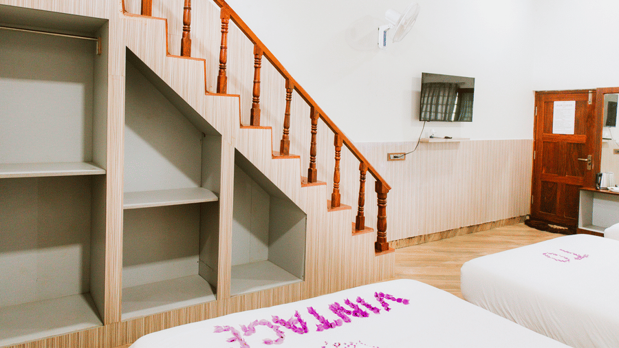 A spacious room featuring tiled flooring, a wooden staircase, a small decorative cart, and a wooden ceiling | Vintage Trails By Ilara