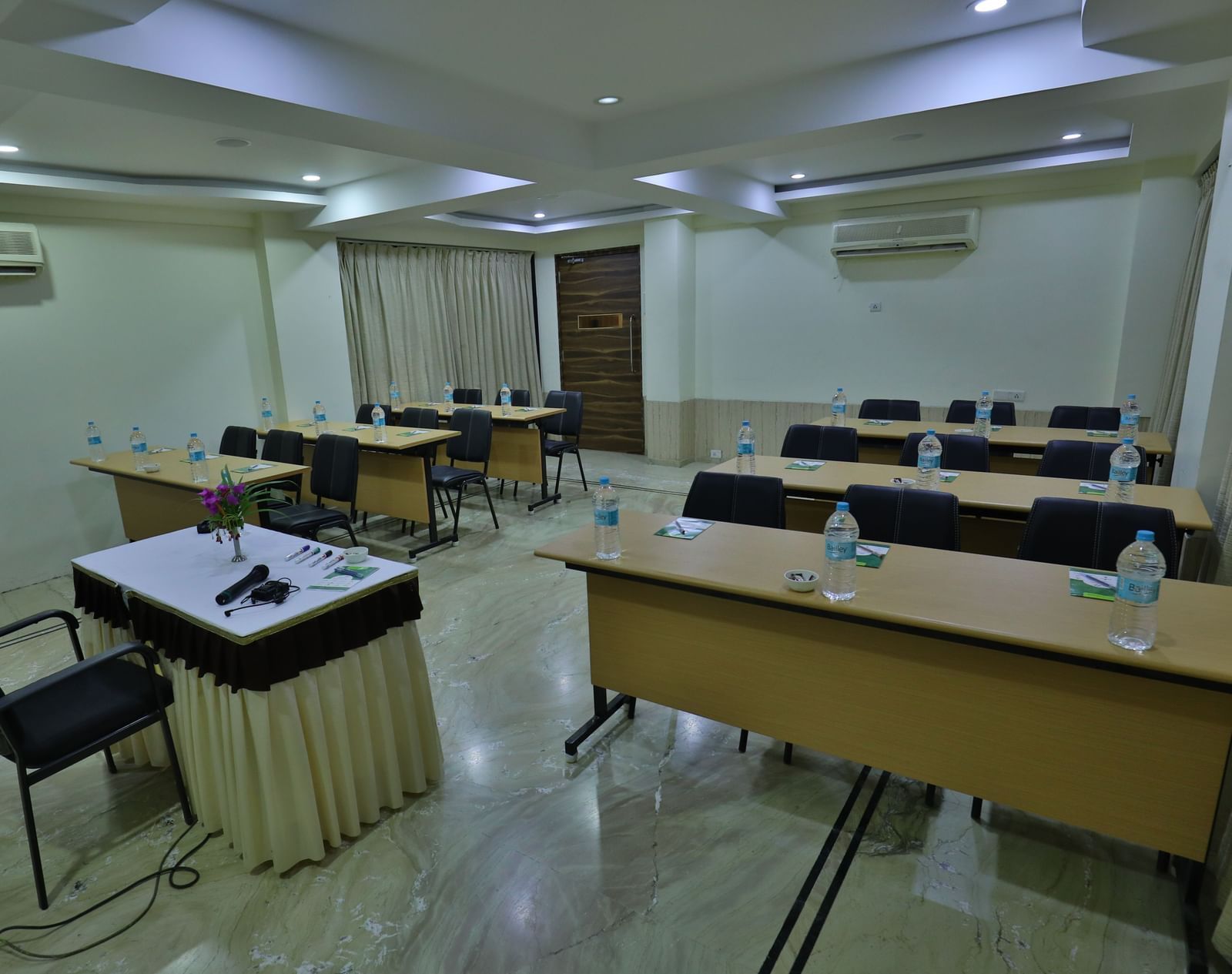 A conference room featuring multiple tables arranged individually, chairs, and a podium at the front - Retreat Heritage, Lonavala