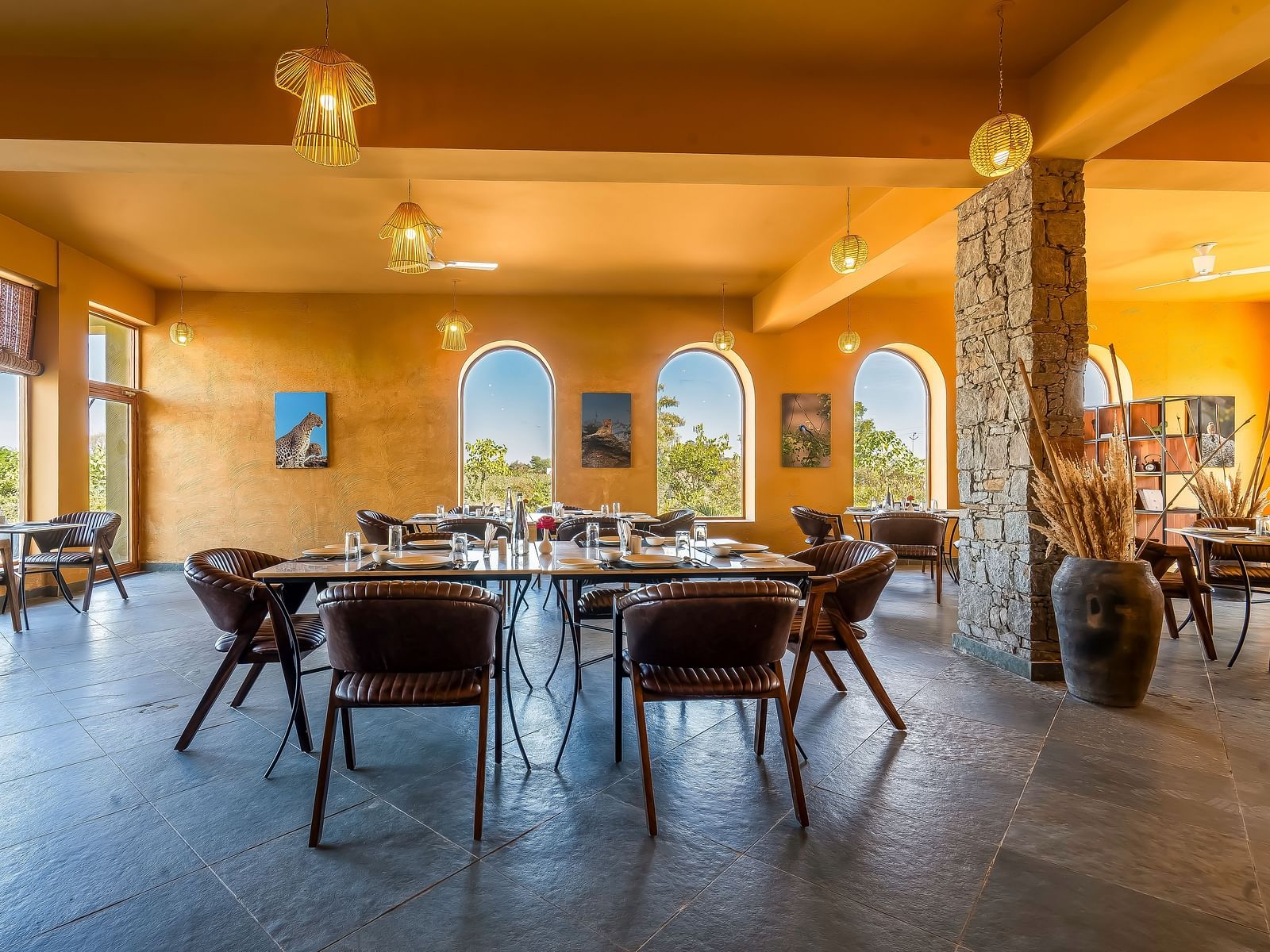 An image of L cave restaurant in Kurja Jawai with glass walls and U shaped entrances featuring bohemian style, and the space is filled with chairs and tables