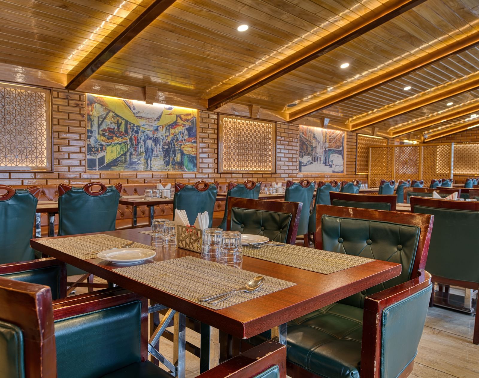 Well-lit dining area with wooden interiors and green chairs at Royal Comfort Regency, offering a warm and inviting restaurant setting.