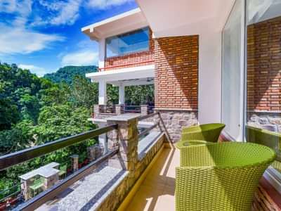 Balcong with seating area and views of the lush plants at Summit By The Ganges Beach Resort & Spa, Rishikesh