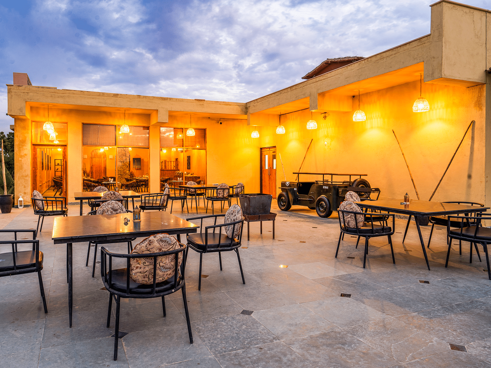 An image of rosettes restaurant featuring several lamps hanging from the roof and various sets of  tables and chairs are placed both indoor and outdoor at Kurja Jawai