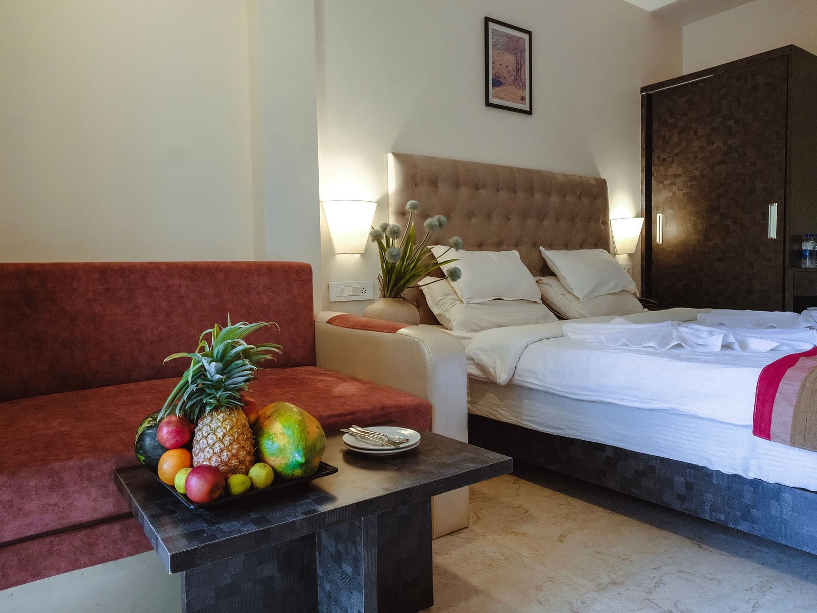 A cosy bedroom with a bed, a red sofa, and a fresh fruit platter on the table – The Verda de Miranda Resort.