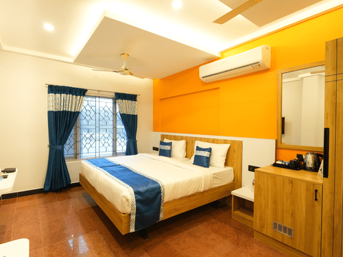 A large bed next to a nightstand in the villaat MGM Whispering Nest, Yelagiri.