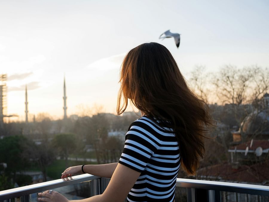 View of a woman standing in a balcony and watching the city.